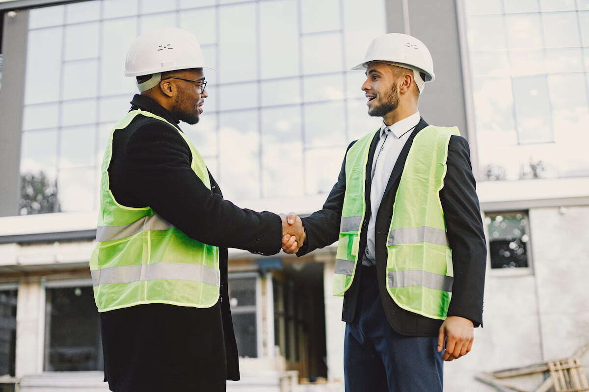 builders-handshaking-outdoors-wearing-uniform-new-glass-building-working-poject-city-infrastructure