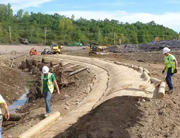 traw blanket installation in progress at a construction site, with workers securing the blankets to prevent soil erosion.